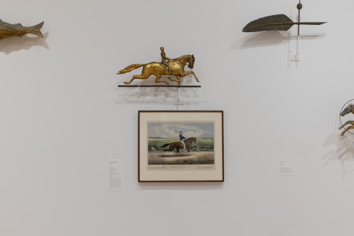 Wall-mounted weathervanes including a gilded horse and jockey above a framed 19th-century print of a horse and jockey.