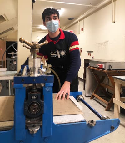 Person working at a blue mechanical press in a workshop.