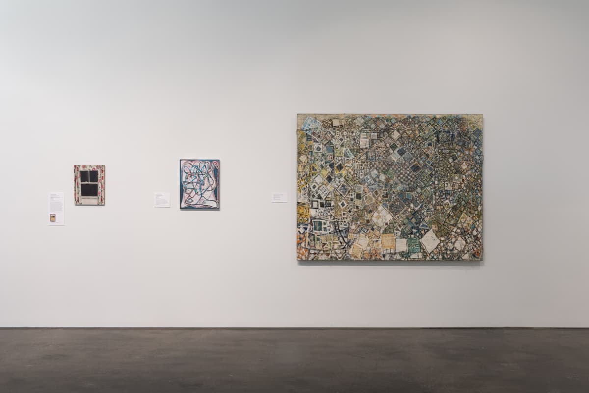 Three artworks on the gallery wall, including a a colorful abstract painting, and a large grid-like composition