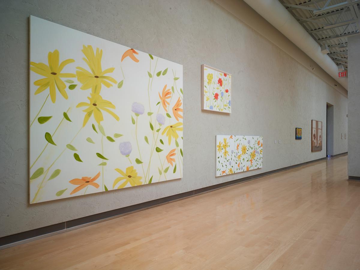 Grey textured gallery wall with group of three floral paintings, each a different dimension but with a consistent soft pastel color palette.