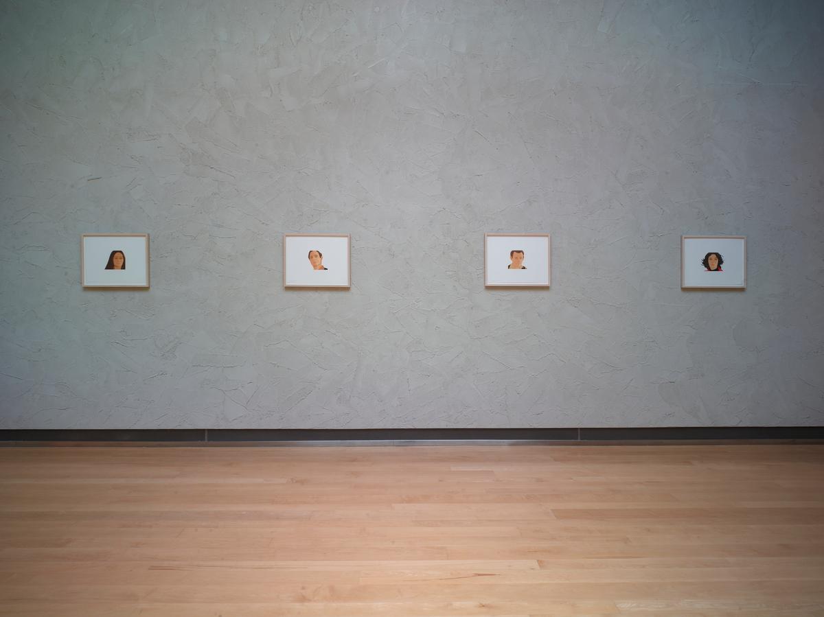 Four small framed portrait illustrations evenly spaced on a textured gray wall above a polished wooden floor.