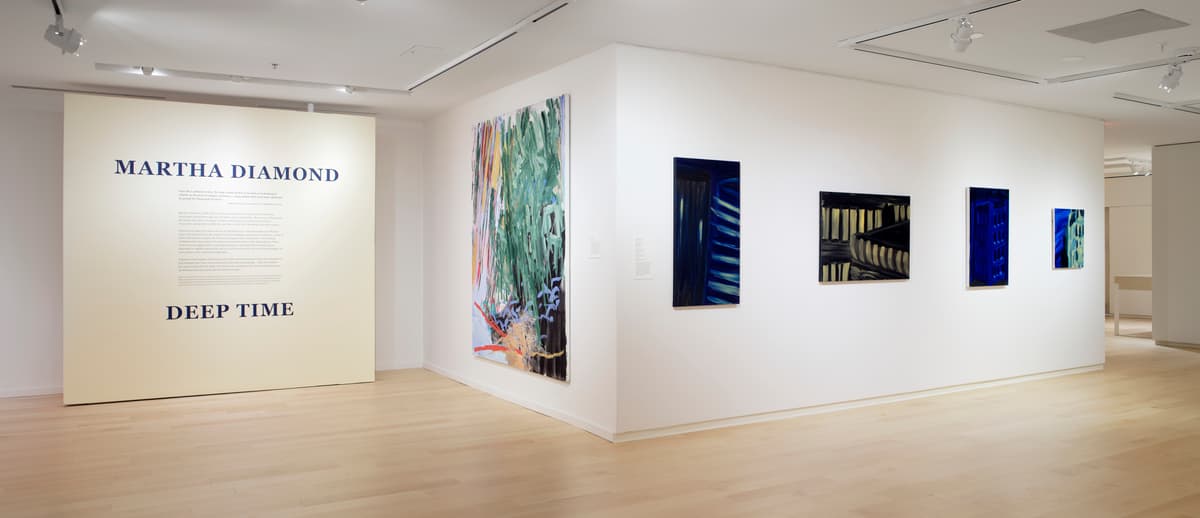 Introductory wall text beside a corner gallery wall displaying large-scale paintings in bold colors.