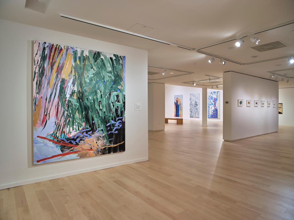 Large expressive painting in green, pink, and black tones displayed on a white wall with a view into adjacent gallery spaces featuring additional artworks.