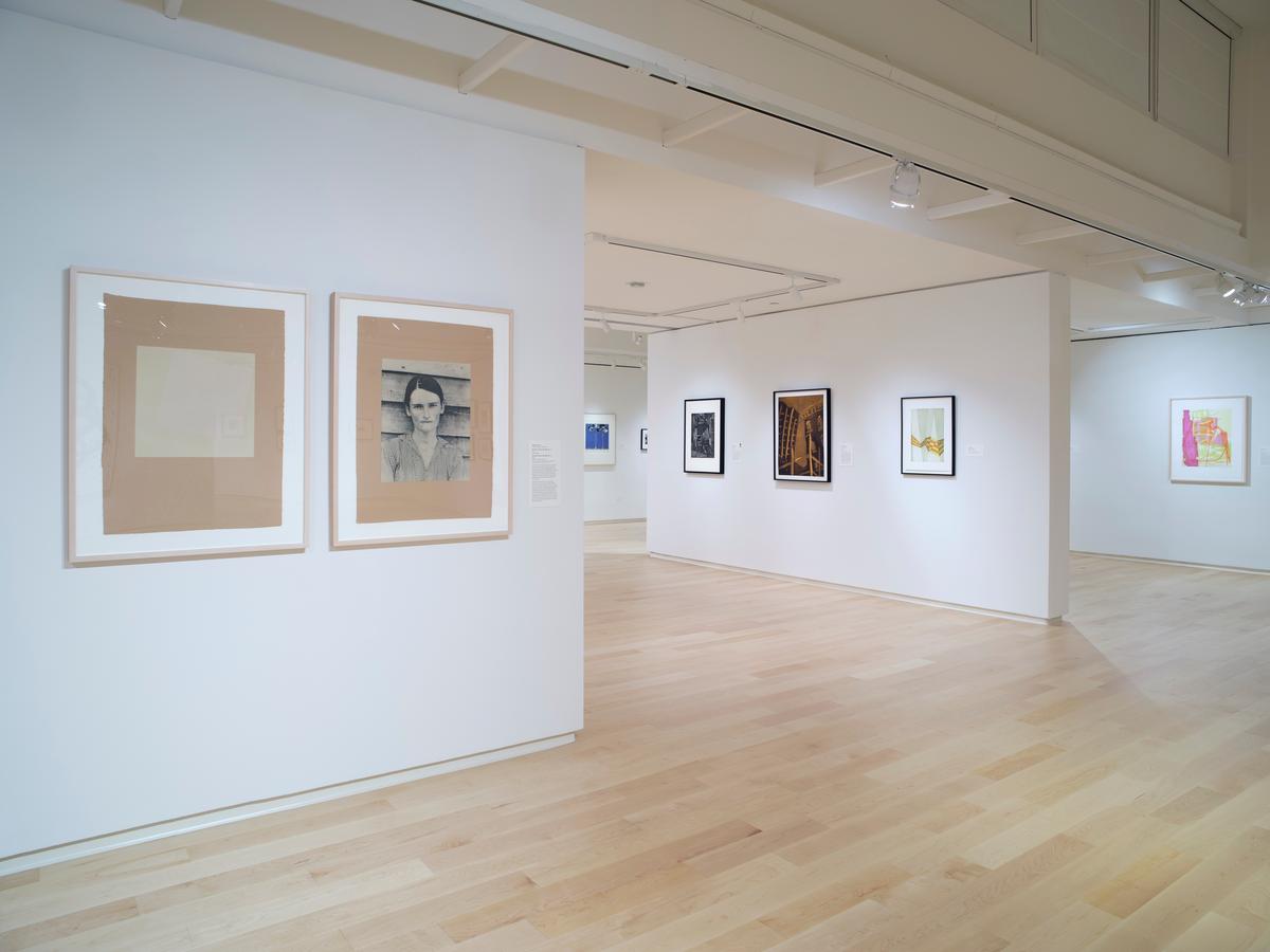Etchings including portrait and abstract prints displayed on white walls in a light-filled gallery with wood floors