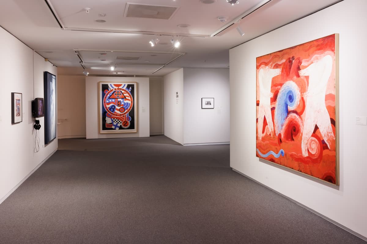 Gallery view including two large hanging works, each with bright red and blue colors and geometric patterns.