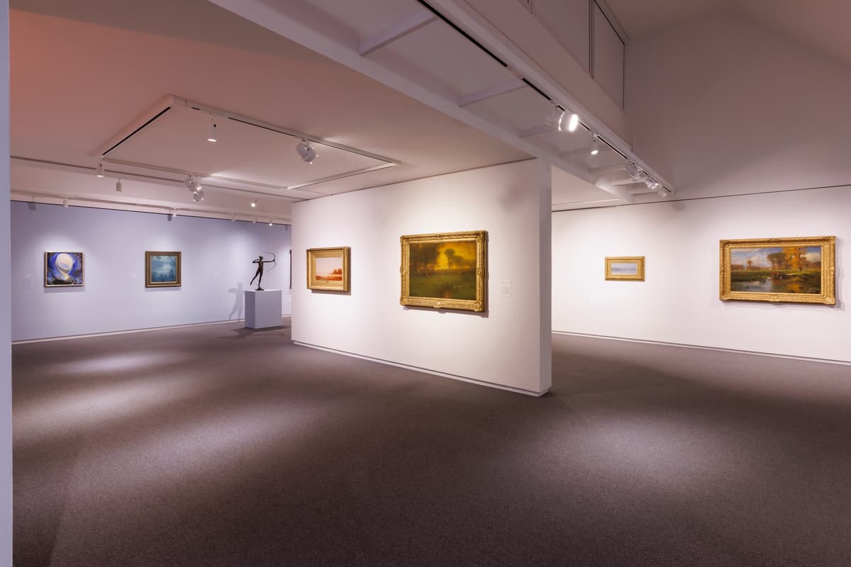 Gallery of framed landscape paintings on white walls.