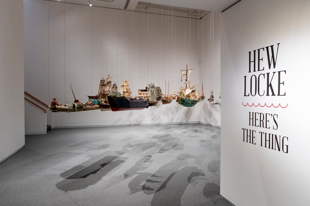 Installation view of the exhibition with suspended ship sculptures in a gallery space