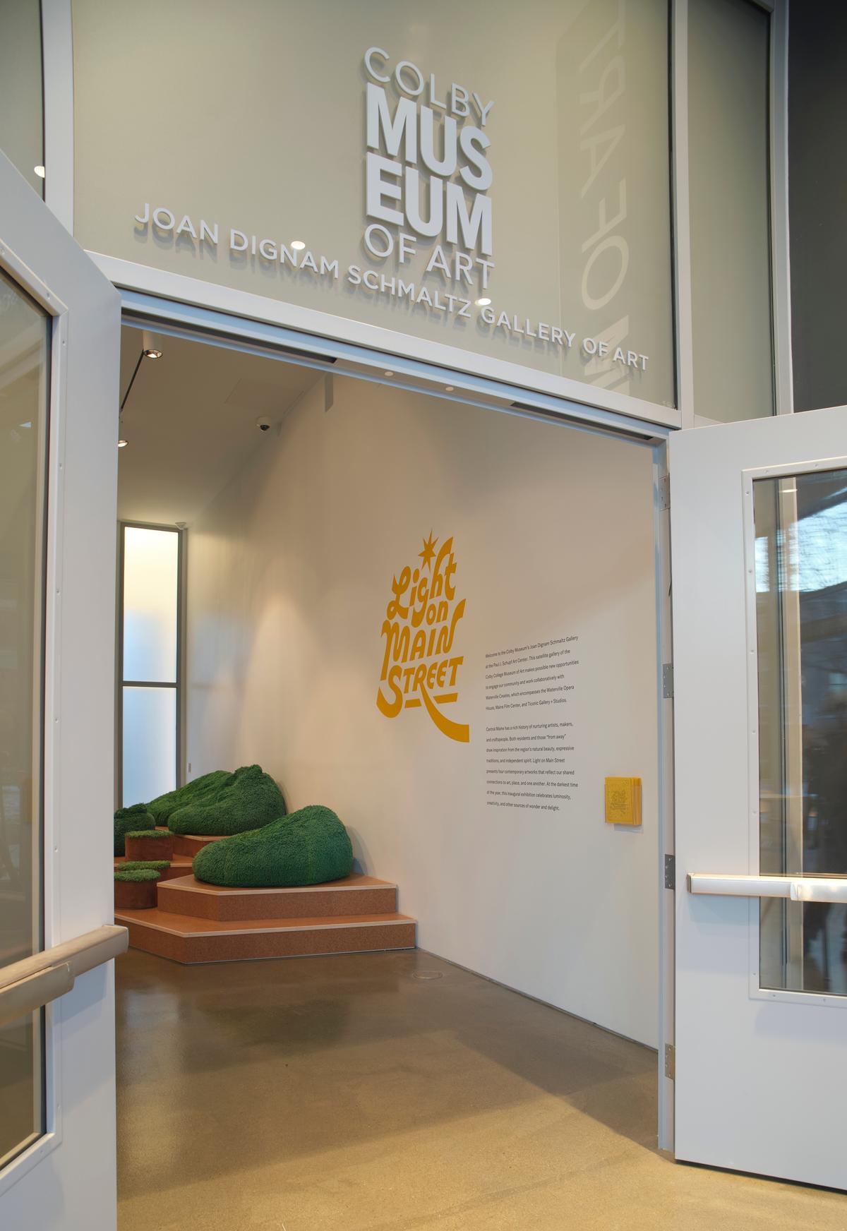 Entrance to gallery: open double doors revealing a yellow text on the wall that reads “Light on Main Street.”