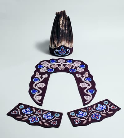 Decorative garment pieces and a headdress arranged on a light background