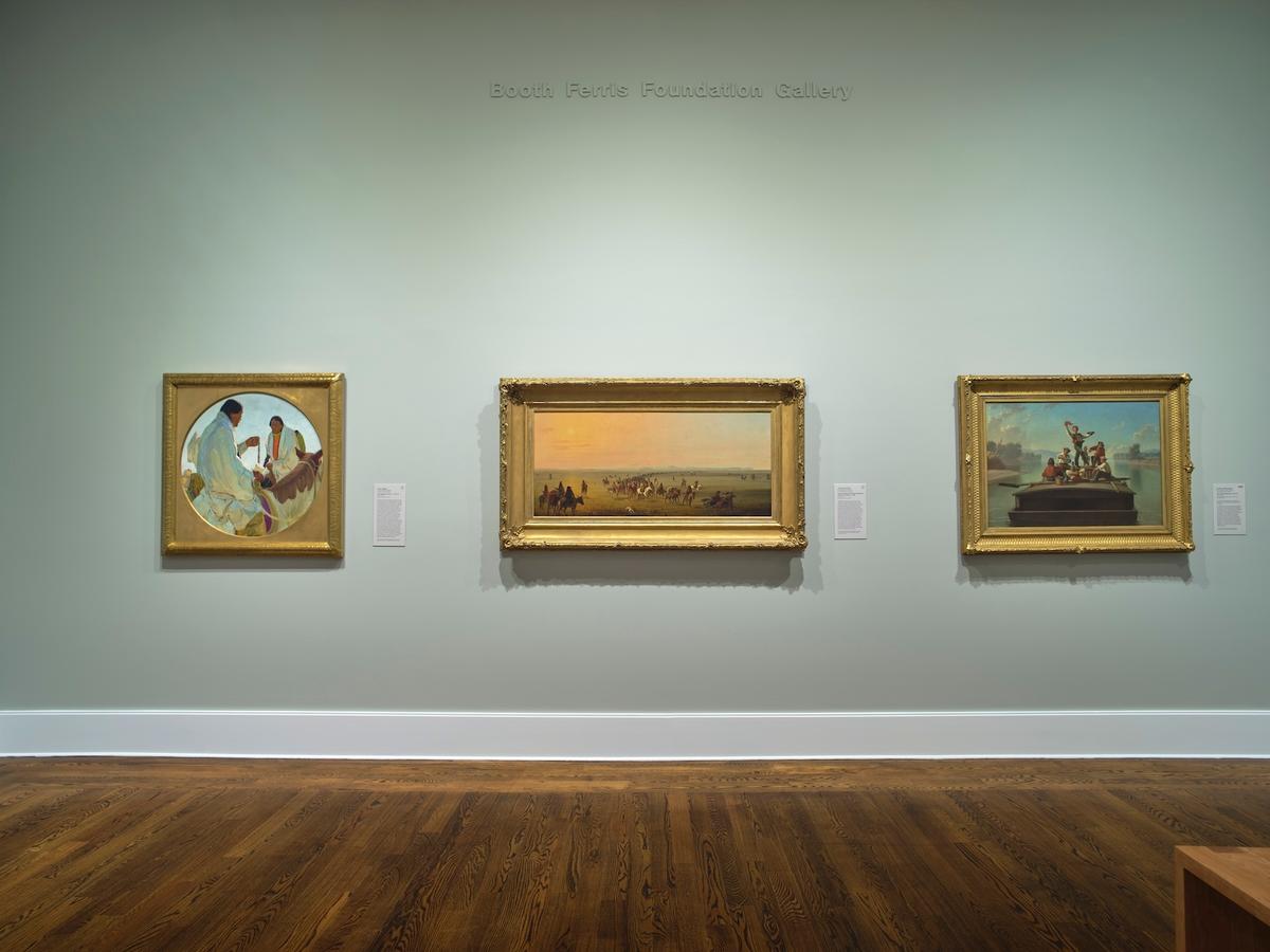 Three framed paintings on a green gallery wall.