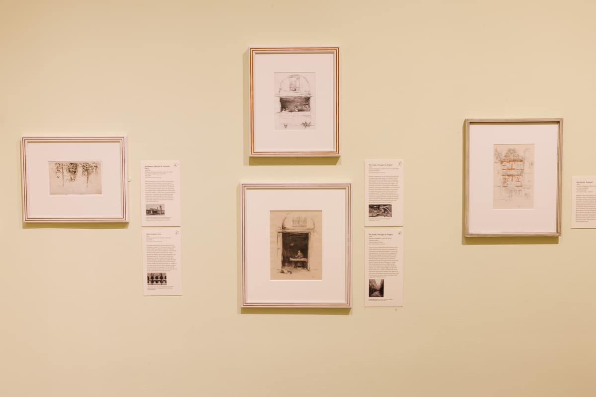 Framed etchings accompanied by interpretive texts on a pale yellow wall.