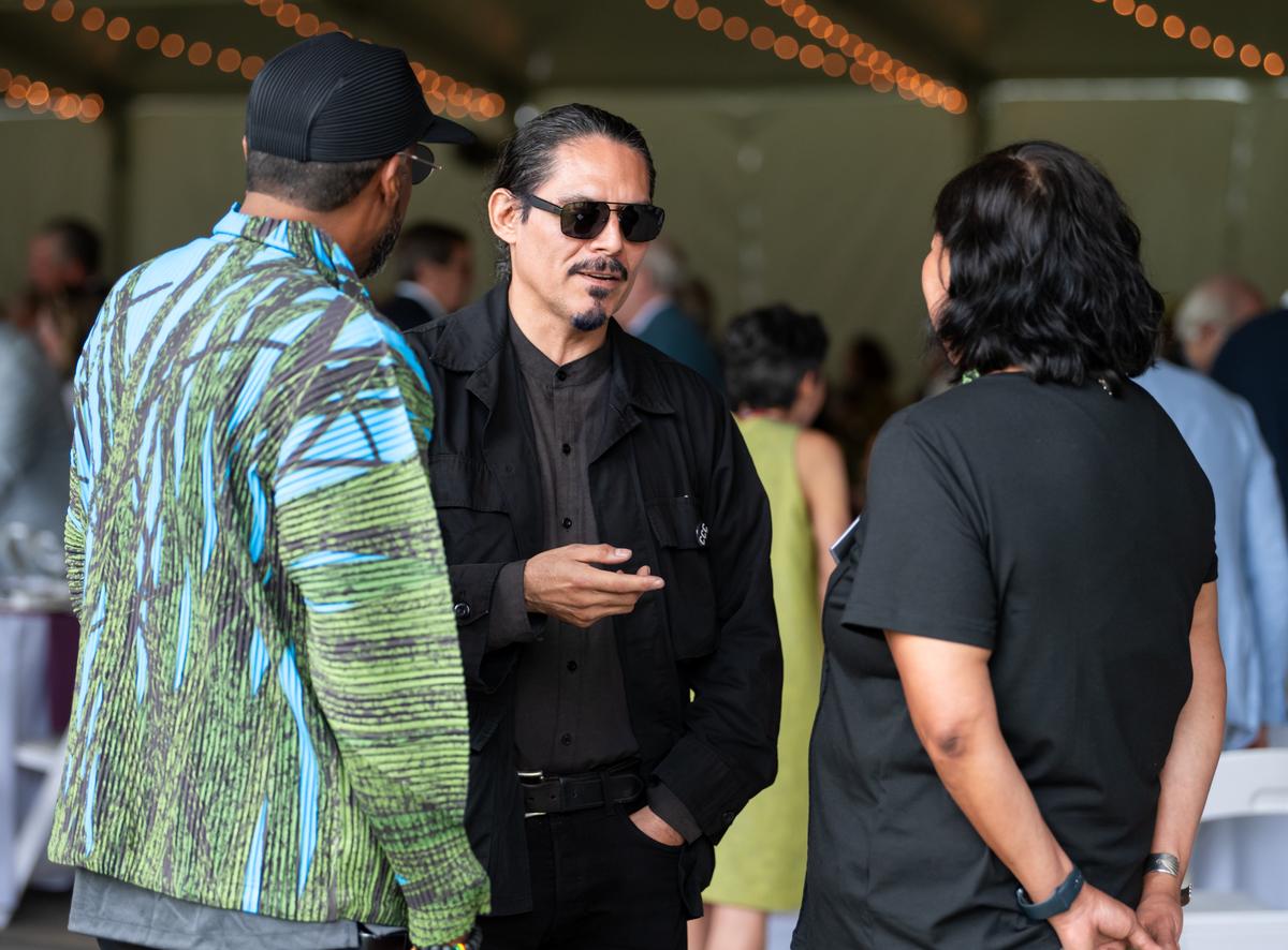 william córdova speaking to Nari Ward and Anna Tsoulahrakis inside an event tent.