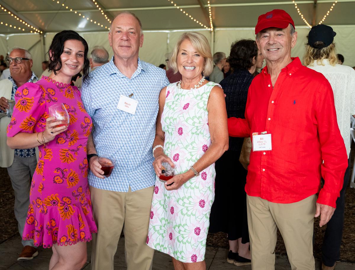 Four individuals including Kevin Gillis and Bill Alfond posed for a picture under a large event tent.