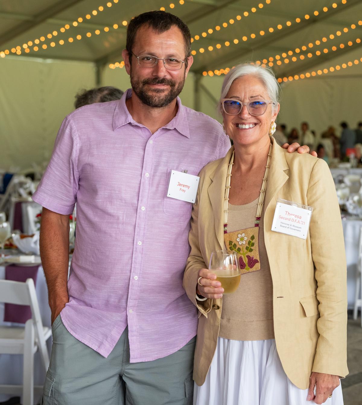 Jeremy Frey and Theresa Secord posed for a picture in a large event tent with string lights overhead.