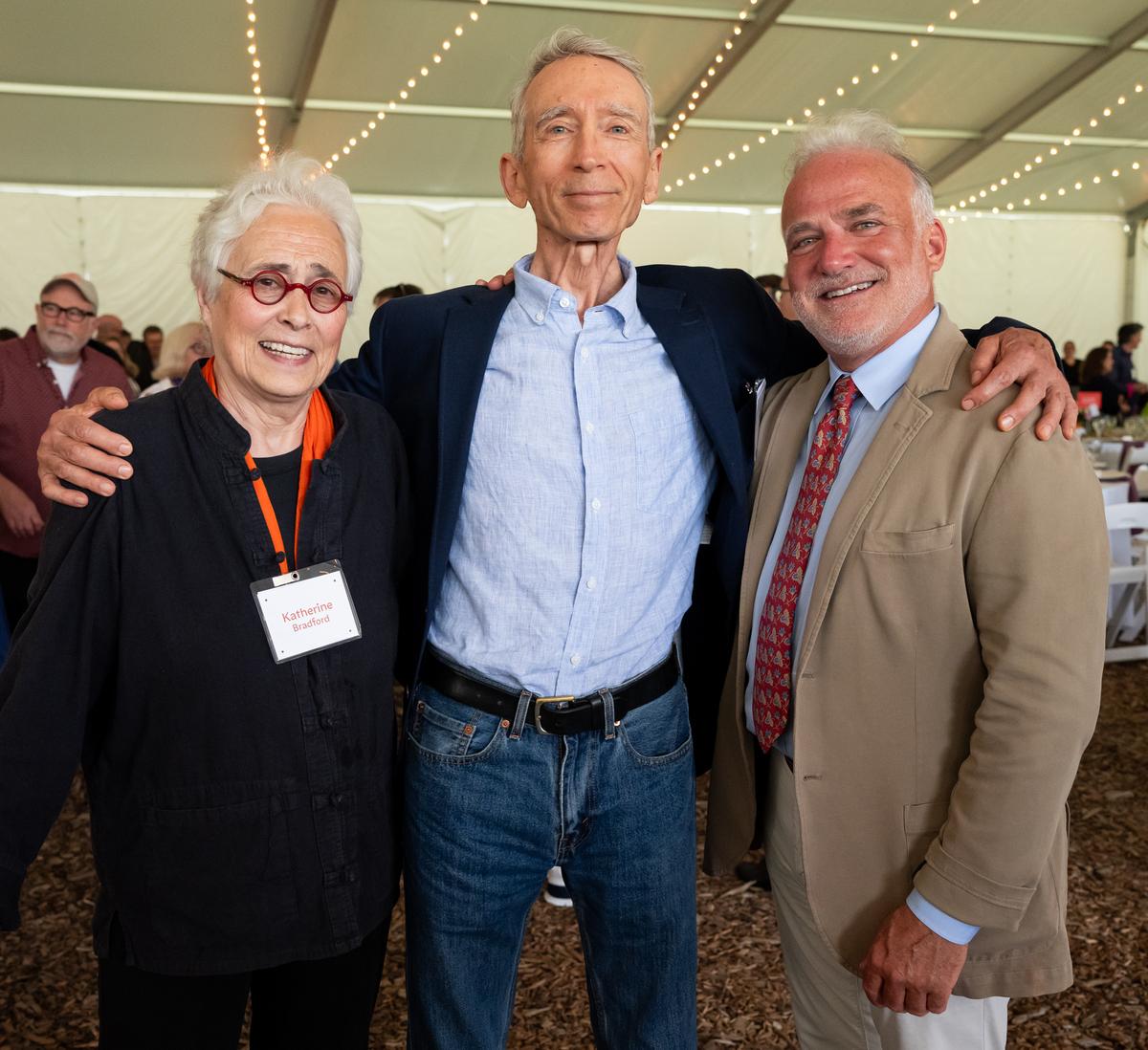 Three individuals including Katherine Bradford and Phil Alexander posed for a picture in an event tent.