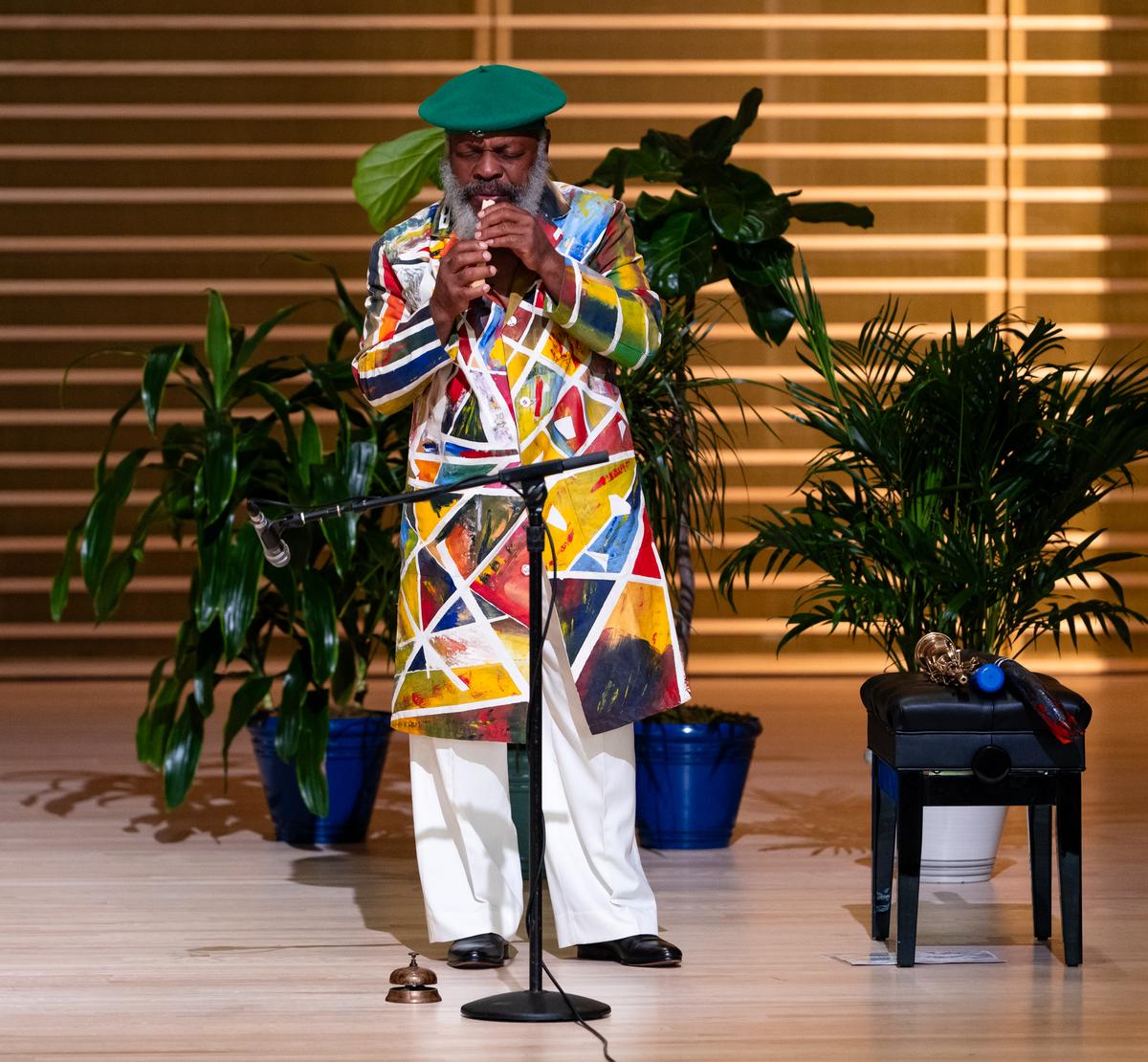 Douglas R. Ewart in a long, colorful jacket playing an instrument on stage