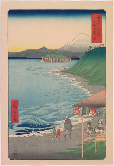 A vertical color woodblock print by Hiroshige from the series "Thirty-six Views of Mount Fuji," showing a coastal scene with travelers. In the distance, the iconic snow-capped peak of Mount Fuji rises above rolling hills and a distinctive, flat, island formation covered in green vegetation. In the foreground, a sandy beach leads to a bright blue sea with white-capped waves. Figures, including a man and two children, walk on the beach toward a small open-sided pavilion or tea stall on the right, where a couple sits. Red cartouches with Japanese text are located in the upper right and lower left.