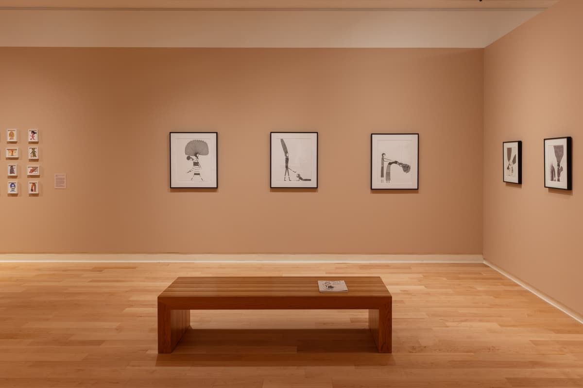 Framed black and white figurative drawings installed on multiple walls in a gallery.