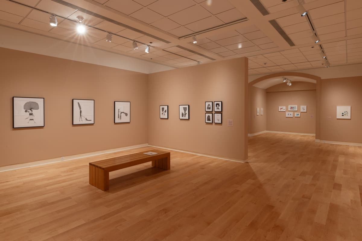 Framed figurative drawings installed on multiple walls in a gallery.