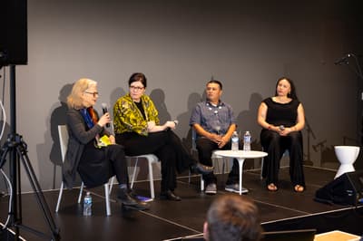 Four individuals seated on a stage with microphones in conversation.