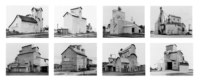 A grid of eight black-and-white photographs, each depicting a different industrial grain elevator. The structures are large, angular, and functional, captured from various angles against plain skies, emphasizing their "anonymous sculpture" quality.