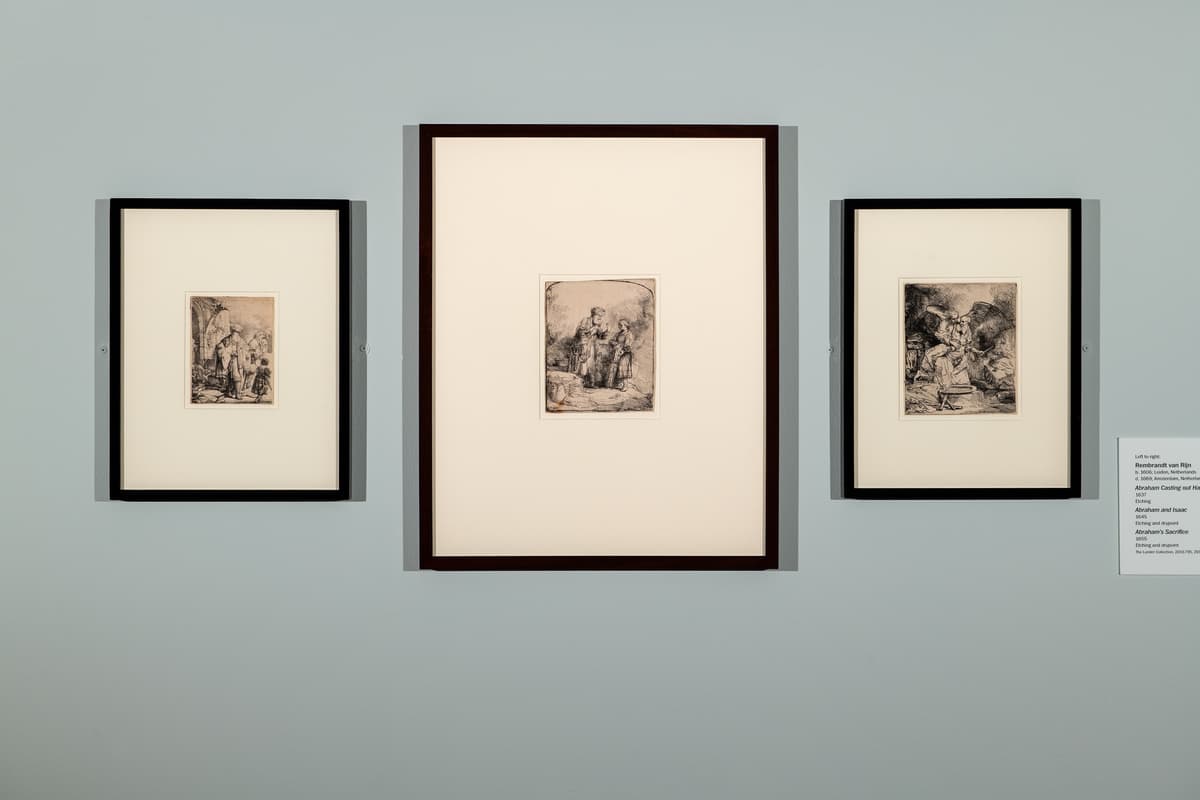 Three small, vertically aligned Rembrandt etchings in black frames with wide white mats, displayed side-by-side on a gallery wall.