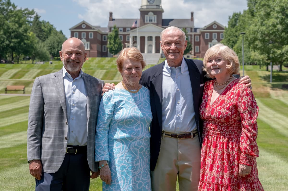 A group of guests at the Summer Luncheon smile for a photo in front of the Miller Library building at Colby College.