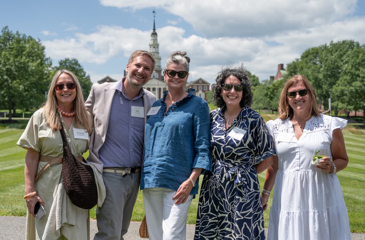 A group of Summer Luncheon attendees smile for a photo in front of the Miller Library at Colby College.