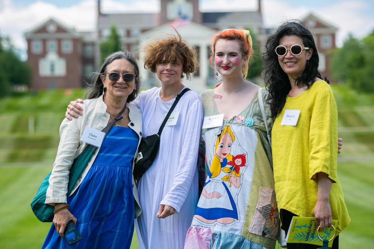 A group of Summer Luncheon attendees smile for a photo in front of the Miller Library at Colby College.