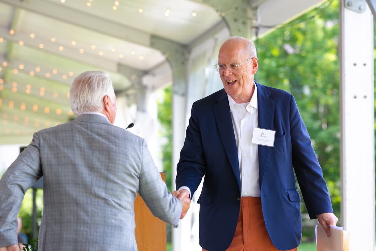Jim Ffrench and President David A. Greene shake hands by the podium at the Summer Luncheon.