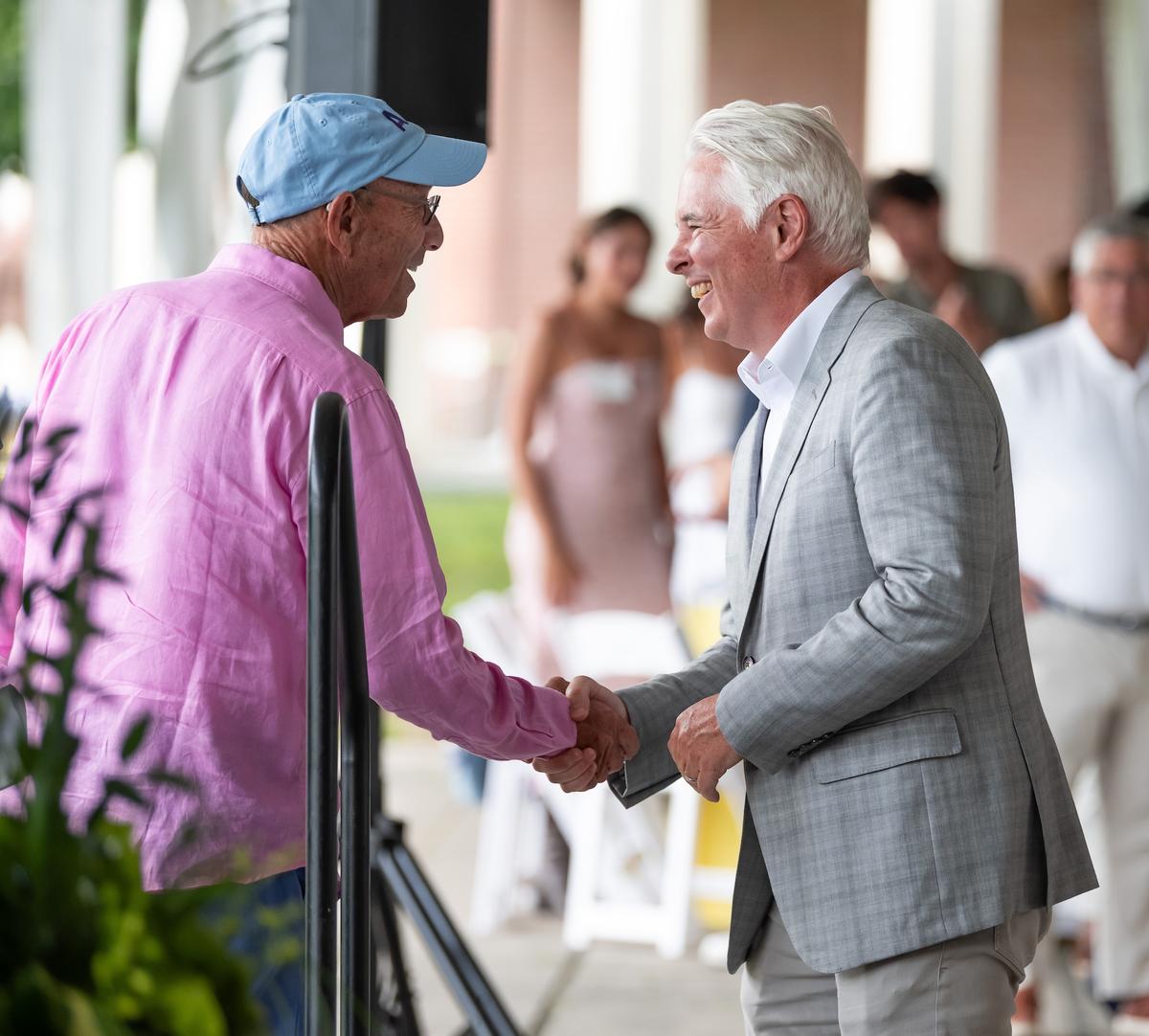Two people shake hands at the Summer Luncheon.
