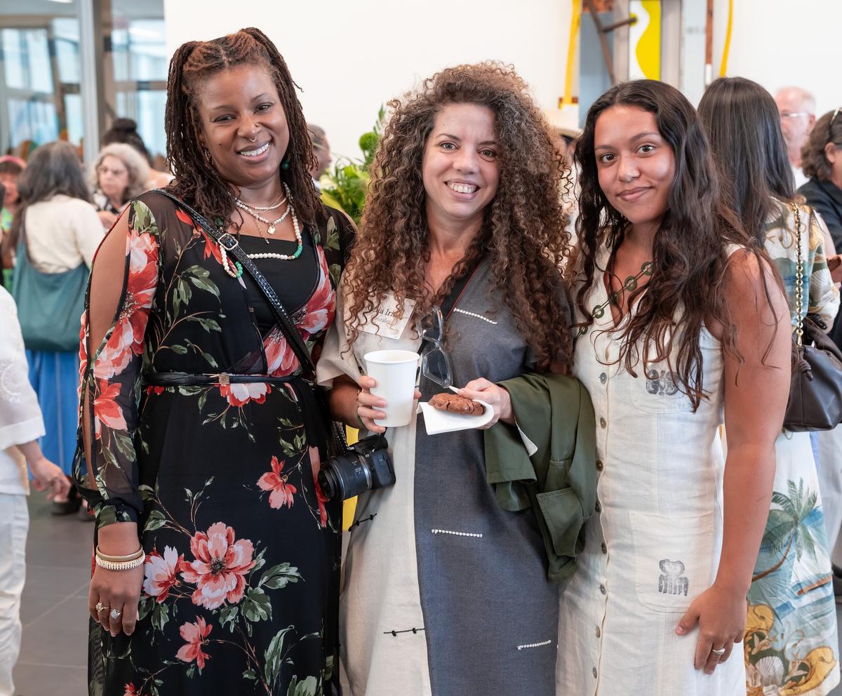 Three artists smiling for a photo at a reception in the museum lobby.