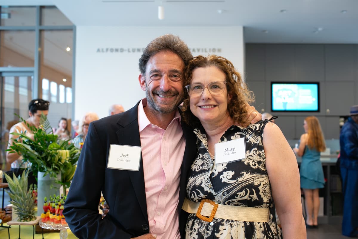 Two people smiling for a photo at a reception in the museum lobby. Their name tags read, "Jeff DiSandro" and "Mary DiSandro".