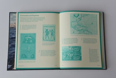 An open multi-page book or catalog rests flat against a light-grey background. The book is open to a double-page spread with a light-cream background and teal-green borders, text, and illustrations. The left page features a section titled "Encounters and Ruptures" in large teal lettering, alongside smaller text columns, an illustration of a sailing vessel, and a small drawing of two standing figures. The right page displays a historical map at the top and another detailed illustration depicting figures near palm trees at the bottom.