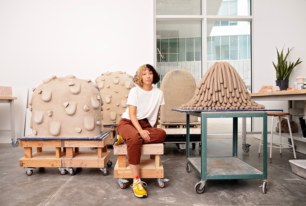 Artist Linda Lopez sitting amongst her sculptural works.