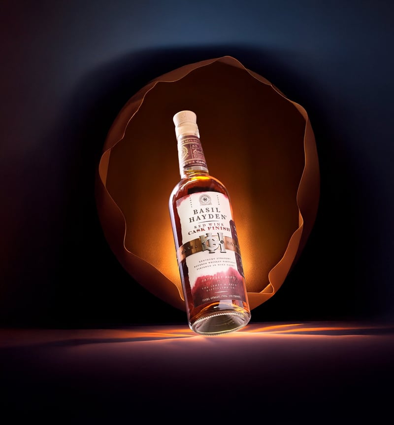A Basil Hayden bottle standing inside a glowing arch of light on a dark ground