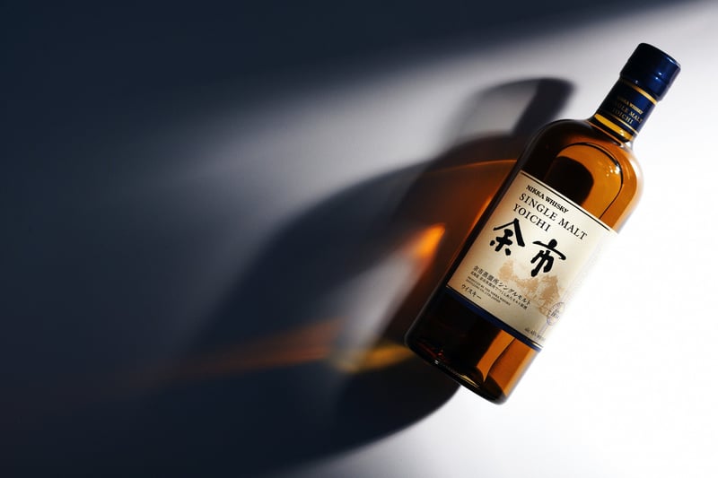 A Nikka whisky bottle on a dark ground, a hard streak of light cutting across the frame behind it