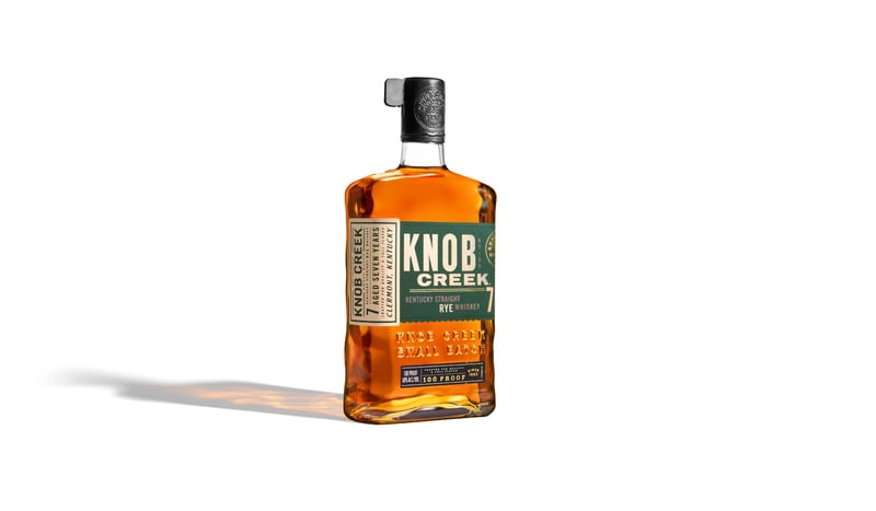 Knob Creek bourbon bottle standing alone on pure white with a long soft shadow to one side
