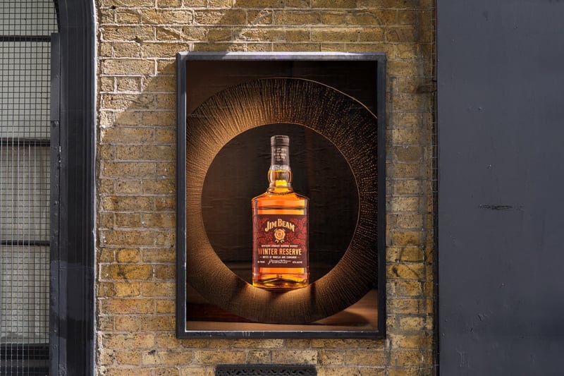 Jim Beam Winter Reserve bottle in a lit alcove set into an old brick wall, dark doorway to one side
