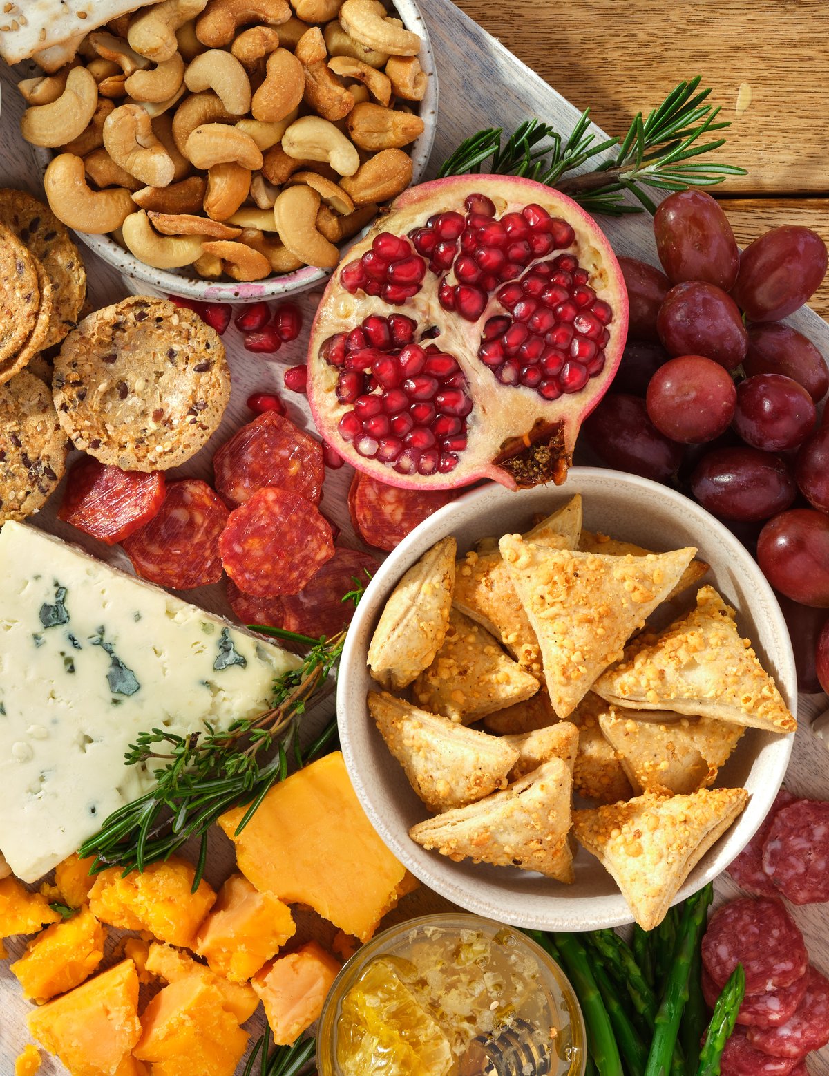 An overhead grazing board of nuts, pomegranate, grapes, cheeses, crackers and cured meats