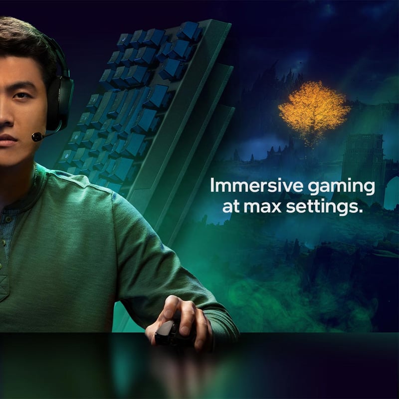 Gamer in a headset at a lit keyboard, a glowing tree and night landscape rendered on the screen beside him