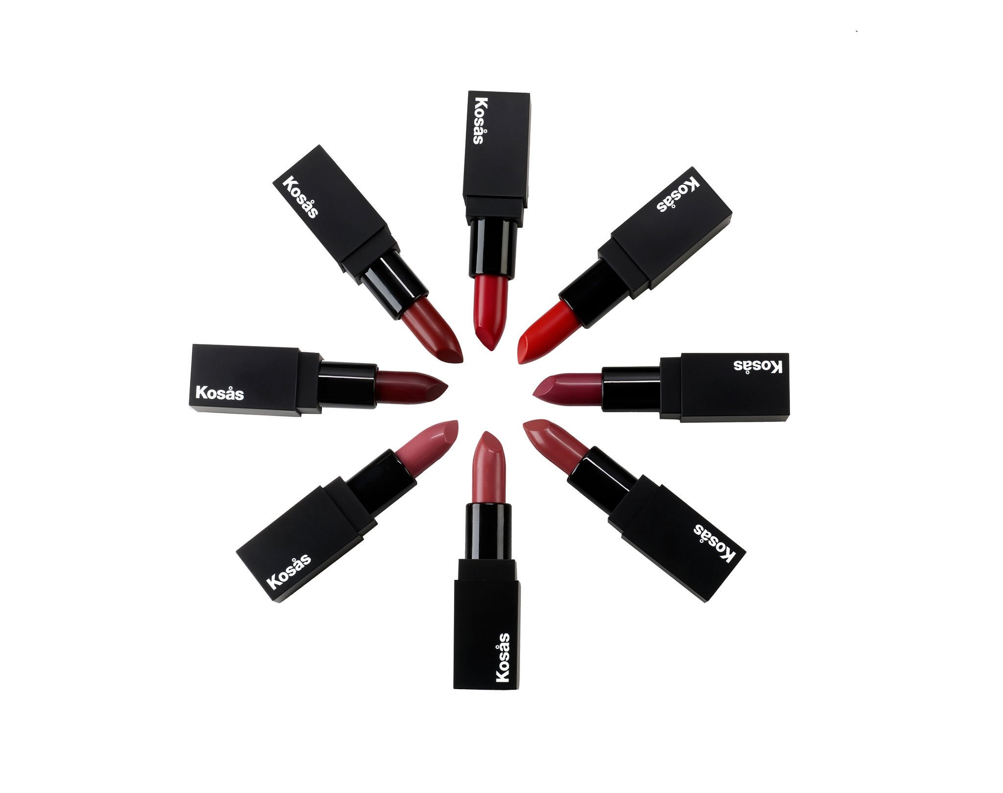 Eight Kosás lipstick bullets radiating from a centre point on white, each tip angled inward to show its shade