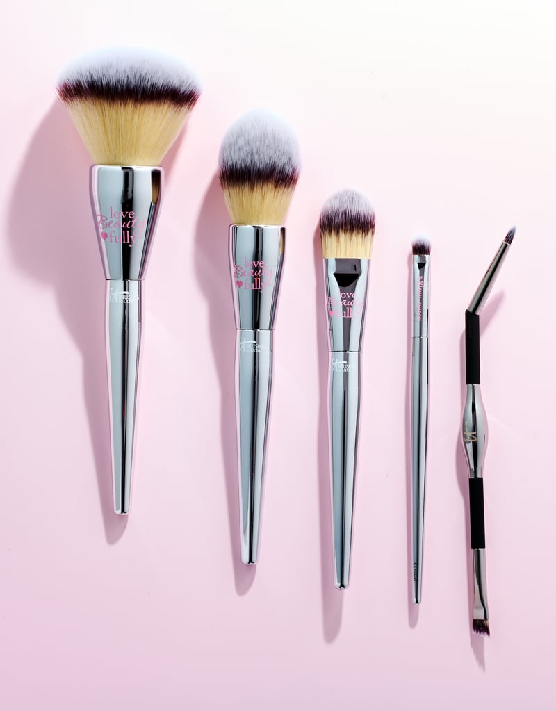 Five makeup brushes fanned in descending size across a pale pink ground