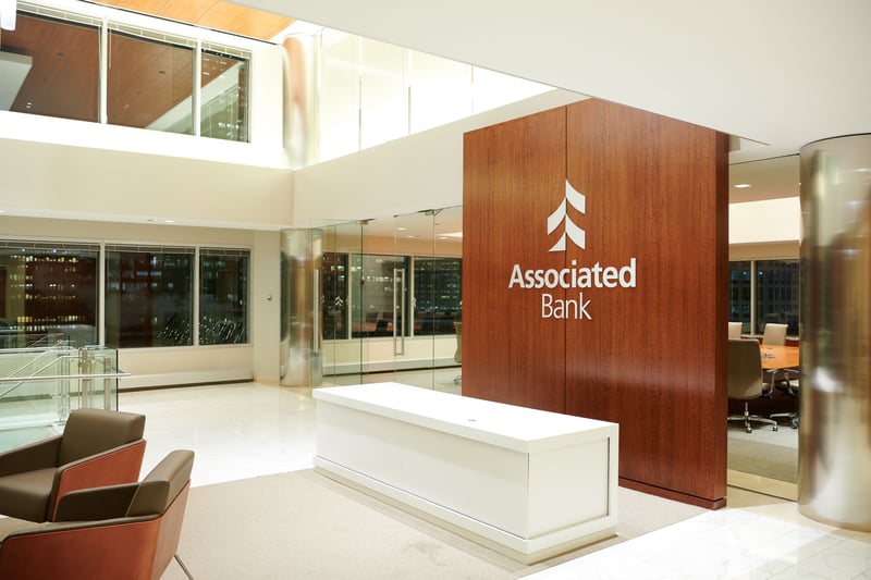A bank lobby with a wood-panelled reception desk and low seating under high windows
