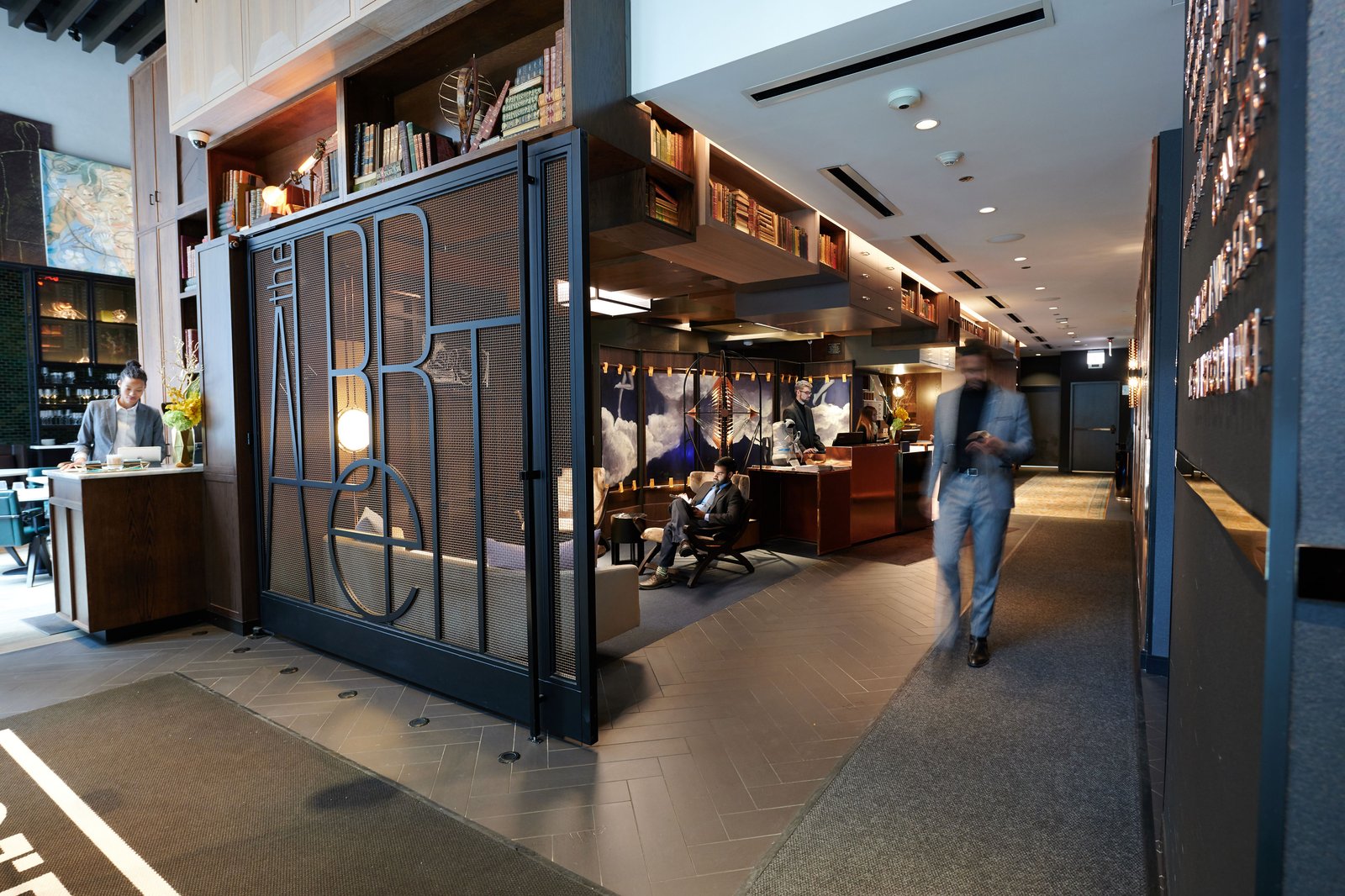 A patterned metal gate opening into a modern bank branch, a figure walking through