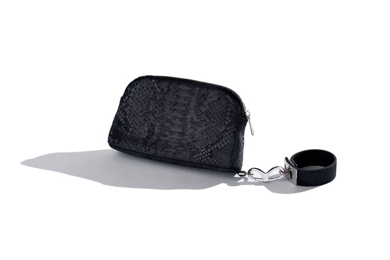 A small black textured clutch bag with a wrist strap, photographed on white