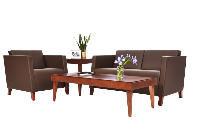 Brown leather armchairs and a three-seat sofa around a cherrywood coffee table with a glass of blue irises, shot on white