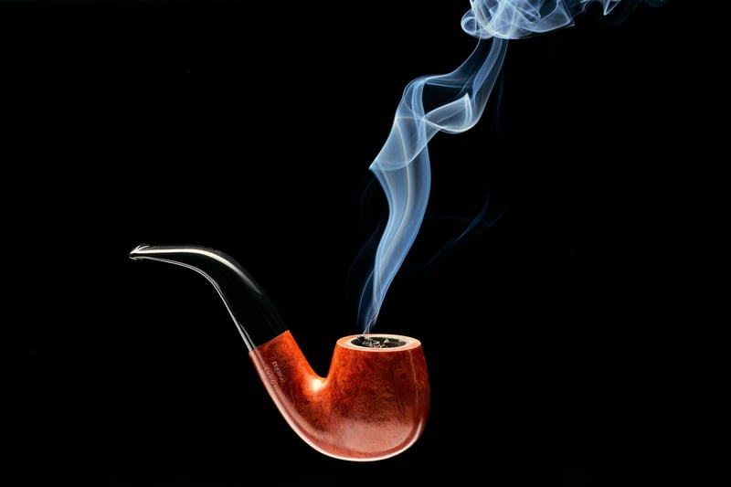 A wooden smoking pipe with a ribbon of smoke rising, shot against black