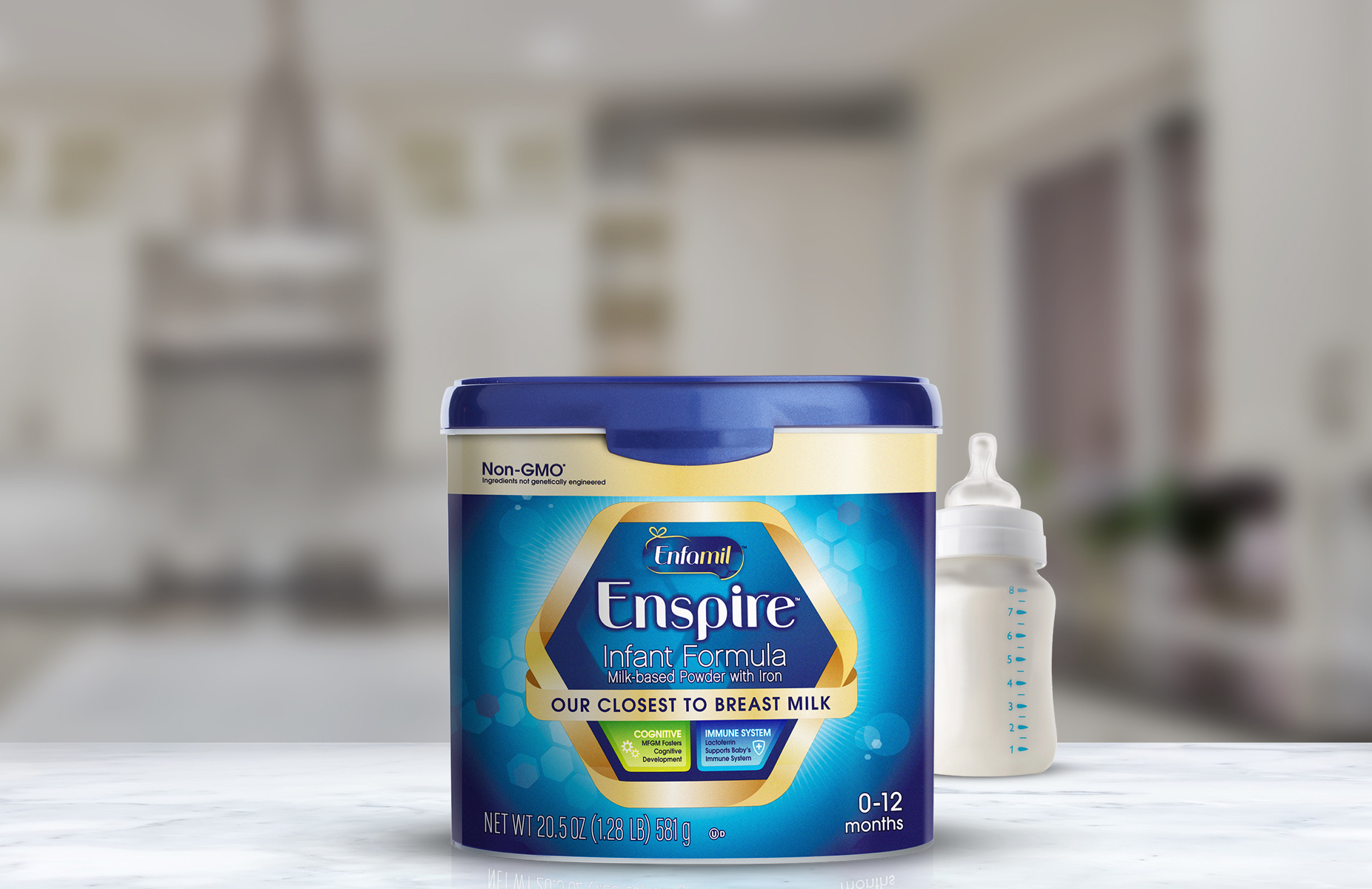 A tub of Enspire infant formula with bottles beside it in a soft-focus kitchen