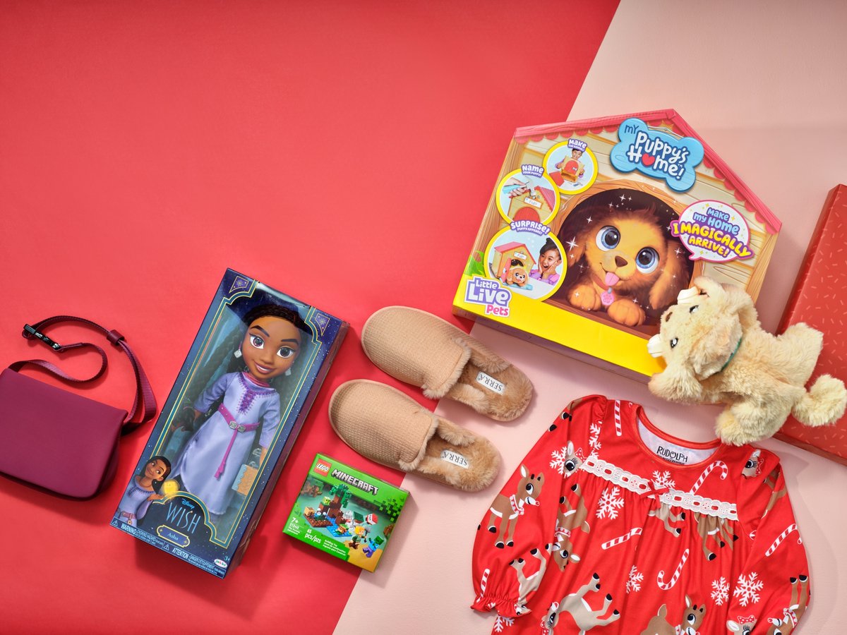 Children's gifts arranged on a pink and red ground — a doll, slippers, a red patterned nightdress and a plush toy